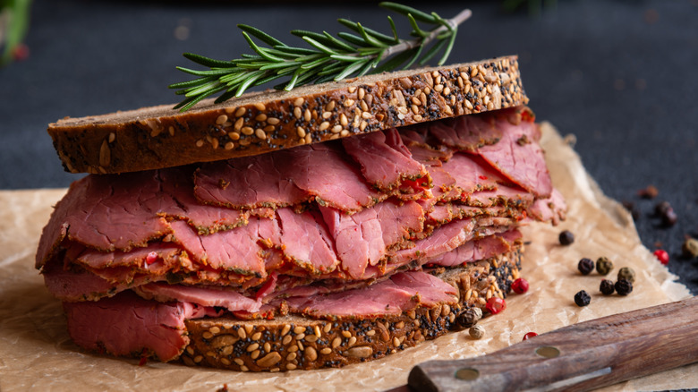 Pastrami sandwich on multi-grain bread with rosemary sprig on top