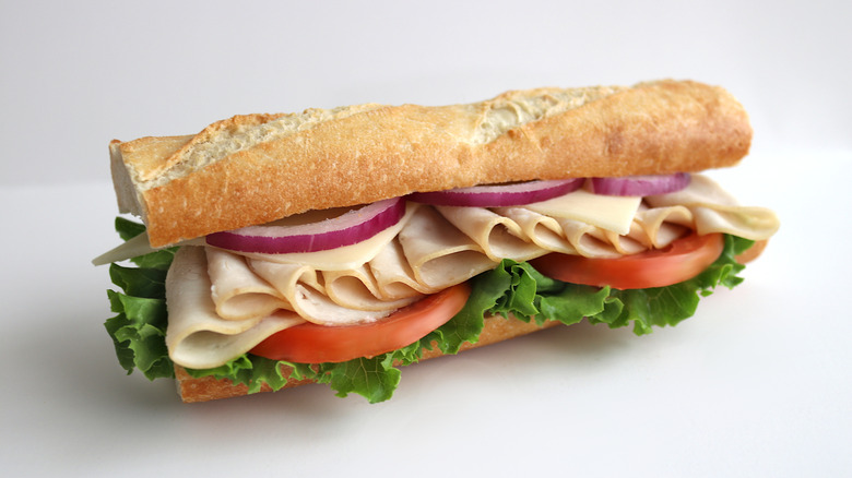 Turkey Baguette Sandwich with Lettuce, Tomato, Onion on white background