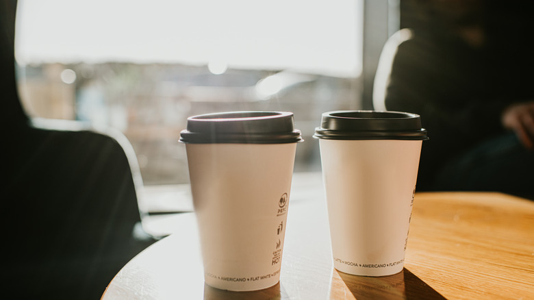 Two cups of to-go coffee on a wooden surface
