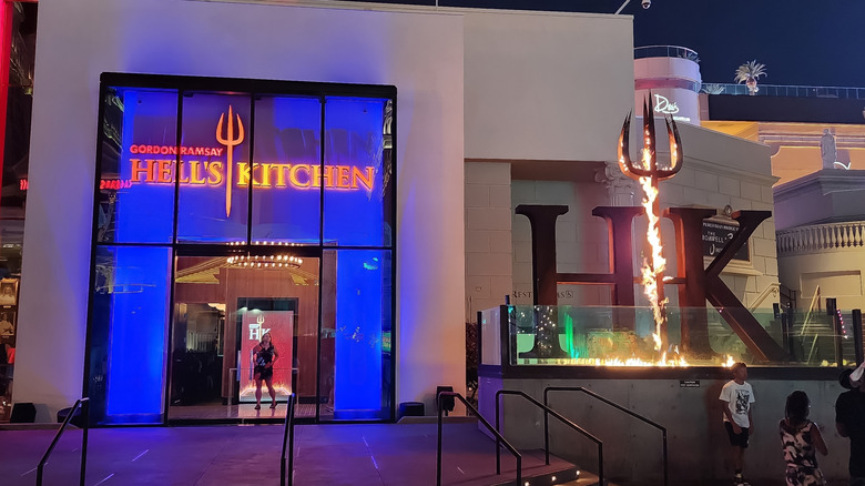 An outside view of a Hell's Kitchen restaurant, with the "HK" torch lit with flames