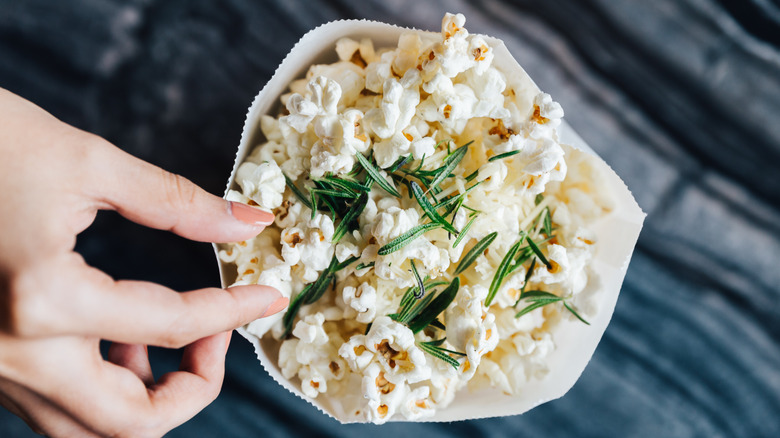 Fingers next to bag of popcorn with rosemary