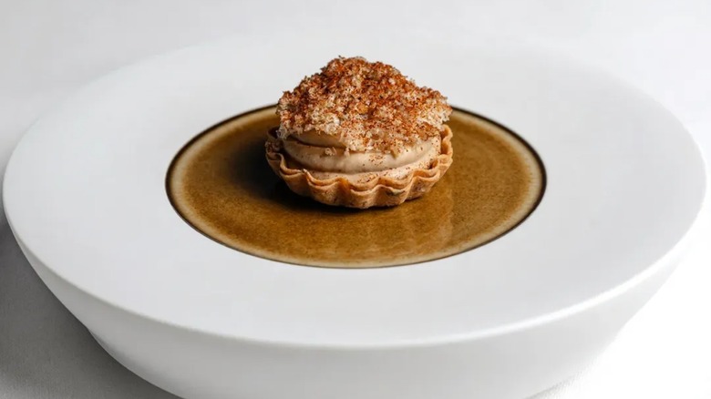 foie gras with huckleberry mole sauce and crushed hazelnuts in a white bowl
