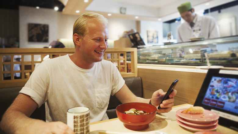 Man sitting at sushi bar with ordering tablet.