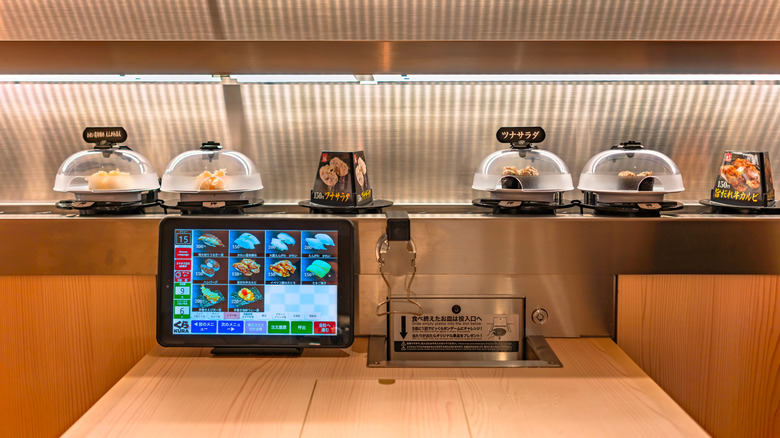 Kura sushi covers on conveyor belt.