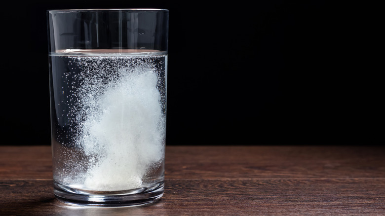 Antacid tablet fizzing in glass of water