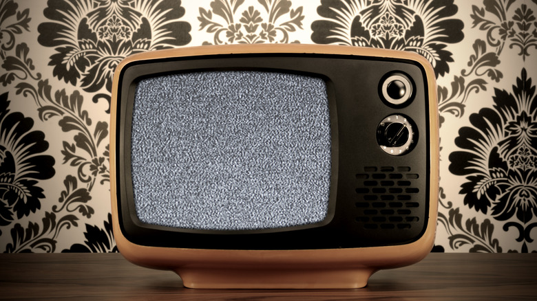 Retro style television in front of ornate wallpaper