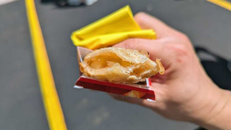 Hand holding partially eaten fried apple pie from McDonald's.