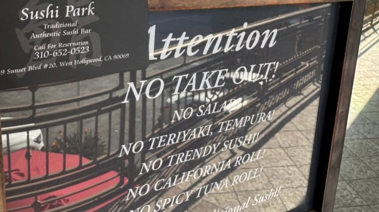 A sign outside of Sushi Park in West Hollywood that says No Take Out alongside a list of foods that they don't serve