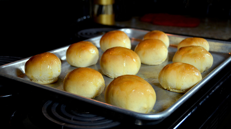 Buttered rolls fresh from the oven sit on a baking sheet