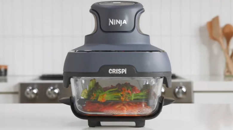 The Ninja Crispi sits on a counter, cooking dinner