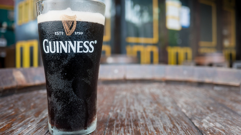 A tall glass of Guinness beer on a wooden surface outside