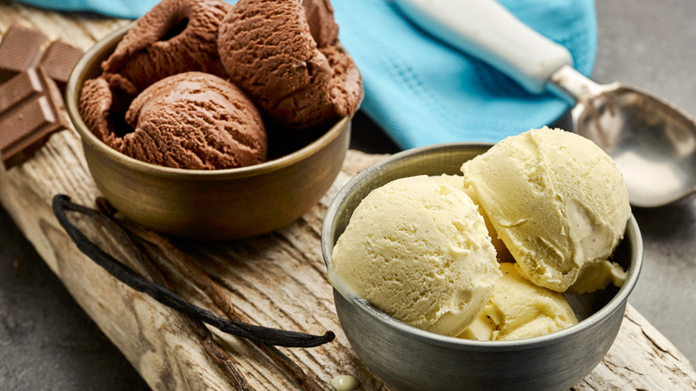 A small metal bowl of vanilla ice cream beside a small metal bowl of chocolate ice cream