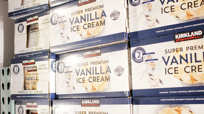 Costco's Kirkland Signature Super Premium Vanilla Ice Cream packs stacked on shelf, and vanilla ice cream next to waffles cones and a metal ice cream scoop