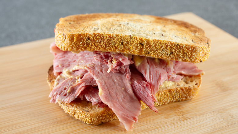 A corned beef sandwich on a wooden cutting board