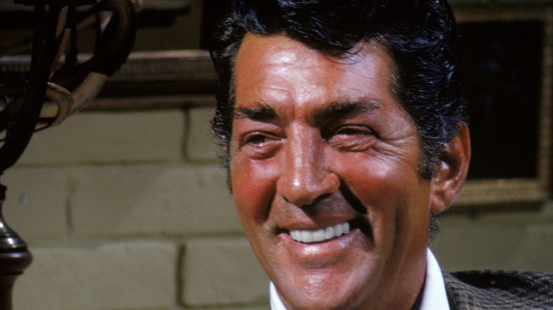 Dean Martin smiling in front of brick wall