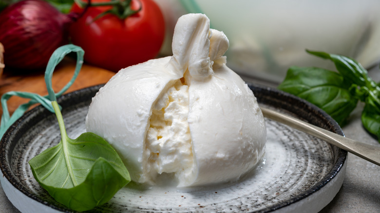 Burrata cheese and fresh basil in a bowl with basil