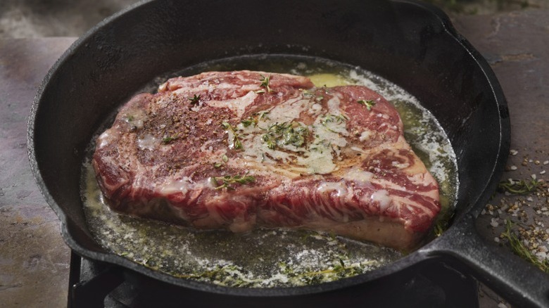 A steak seared in butter in a cast iron frying pan