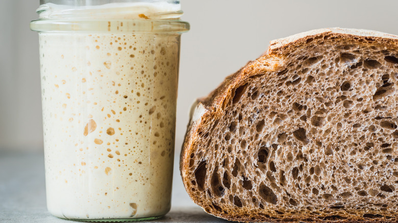 Sourdough starter in glass jar next to bread