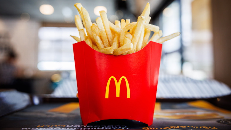 A red paper box of McDonald's french fries on a tray inside the restaurant