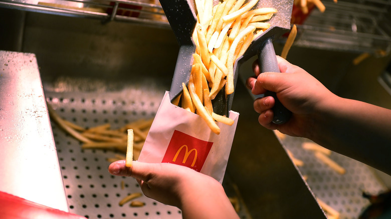 A McDonald's employee fills a small paper sack with french fries