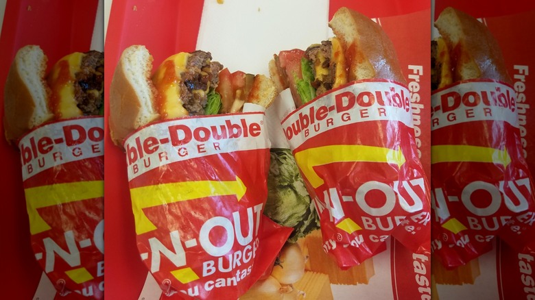 Two halves of a Double-Double burger from In-N-Out in separate wrapping.