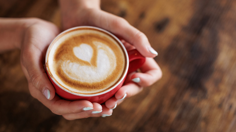 A red cup of coffee held in someone's hands