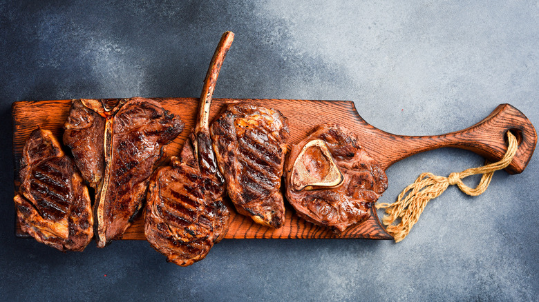 Top view of assorted grilled steaks on wooden cutting board