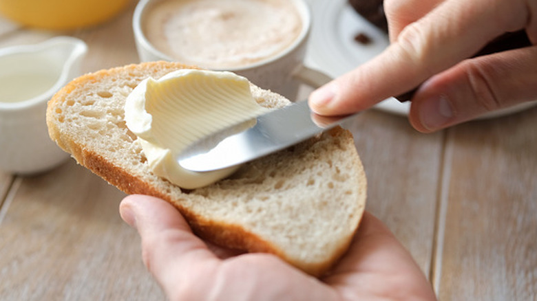 Butter being spread on bread with knife