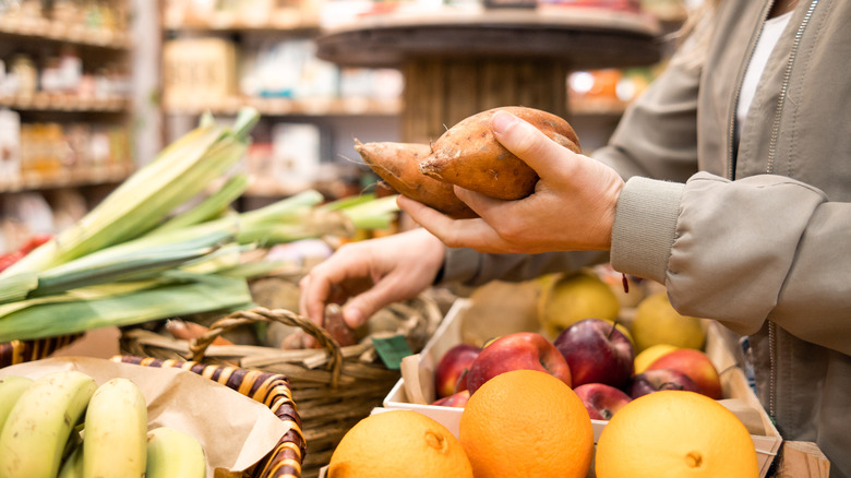 Hands holding potatoes at produce section of market