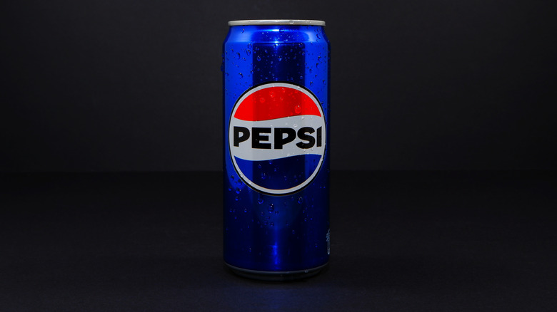 A tall blue can of Standard Pepsi in a black room