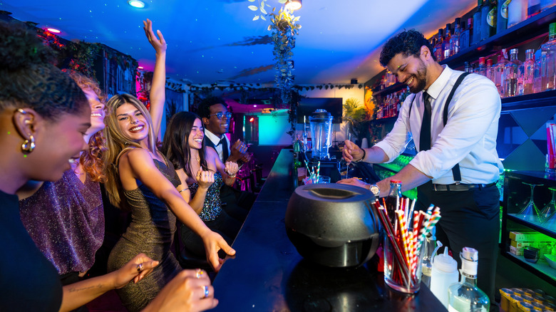 Friends dance while a bartender prepares drinks