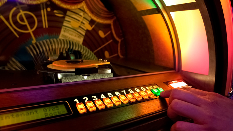 A person presses buttons on an illuminated jukebox