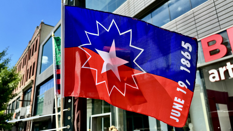 Red and blue flag with Juneteenth date on it on a flag pole