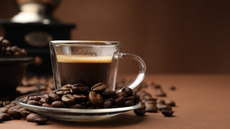 cup of coffee with whole beans and grinder