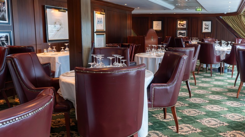 Interior of steakhouse with wood tones, plush seats, and white tablecloths