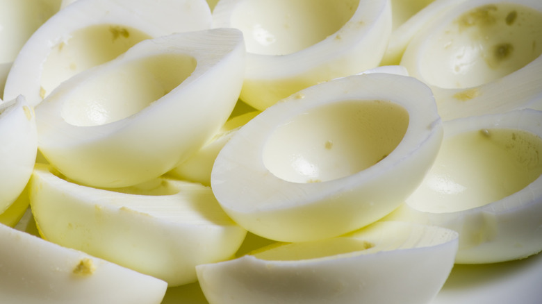 Hollowed out boiled eggs piled up in a dish without any filling.