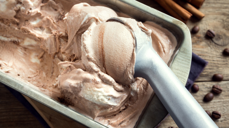 Scooping homemade coffee ice cream from a loaf pan