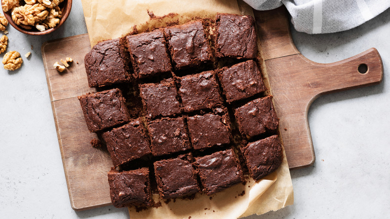 A batch of brownies cut into squares on a wooden cutting board
