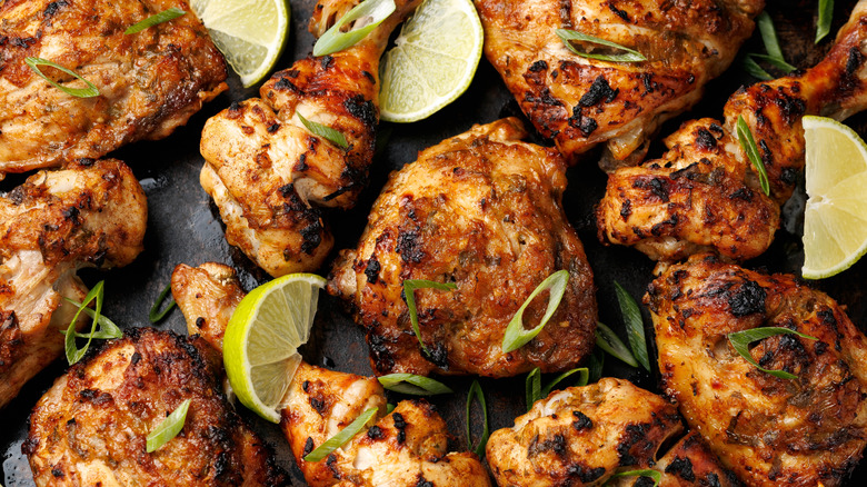 Jerk chicken with lime wedges and fresh herbs