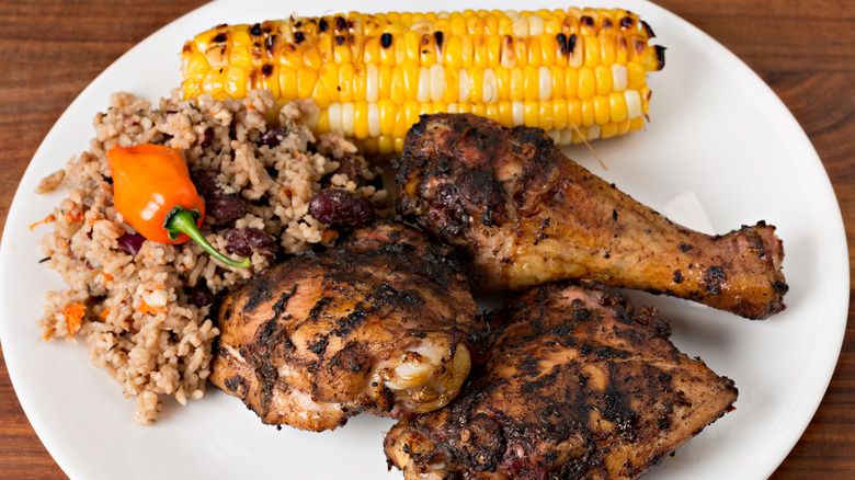 Jerk chicken with rice, corn, and a scotch bonnet pepper