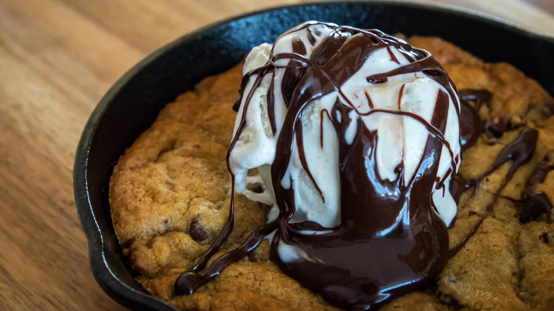 A chocolate chip skillet cookie topped with vanilla ice cream and chocolate sauce