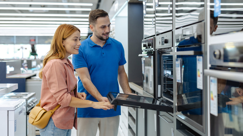 A couple looks inside an oven at an appliance store