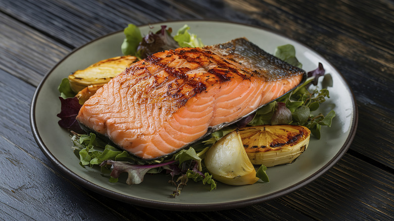 A grilled salmon fillet on a bed of mixed greens