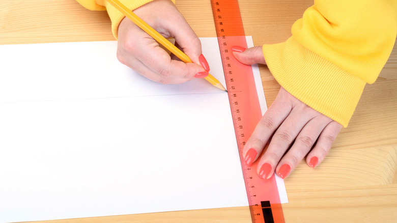 Person using ruler to trace measurements on paper