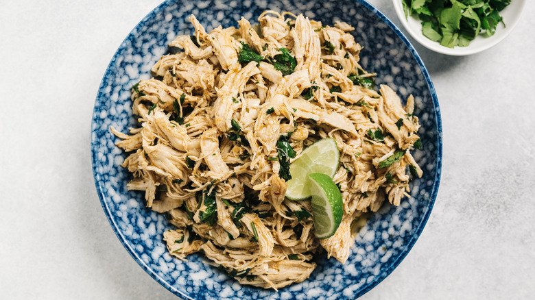 shredded chicken in bowl with cilantro and lime