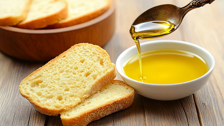 Small dish of olive oil with spoon prepared to drizzle on sliced bread