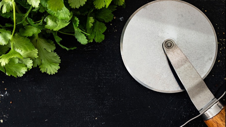 Pizza wheel next to fresh herbs