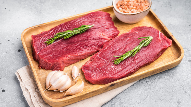 raw ostrich steaks on wooden board