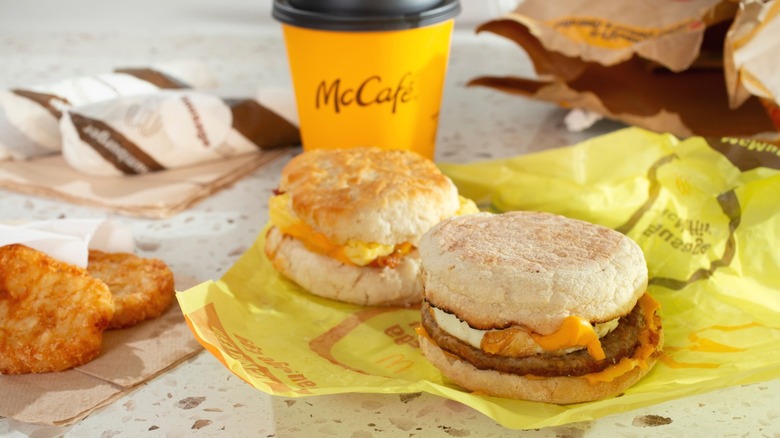 A breakfast from McDonald's, including a Sausage McMuffin, home fries, and a coffee.