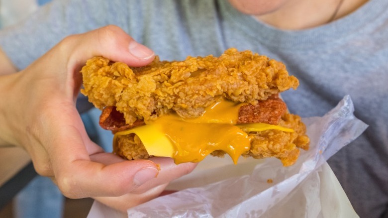 A hand holding the KFC Double Down sandwich.